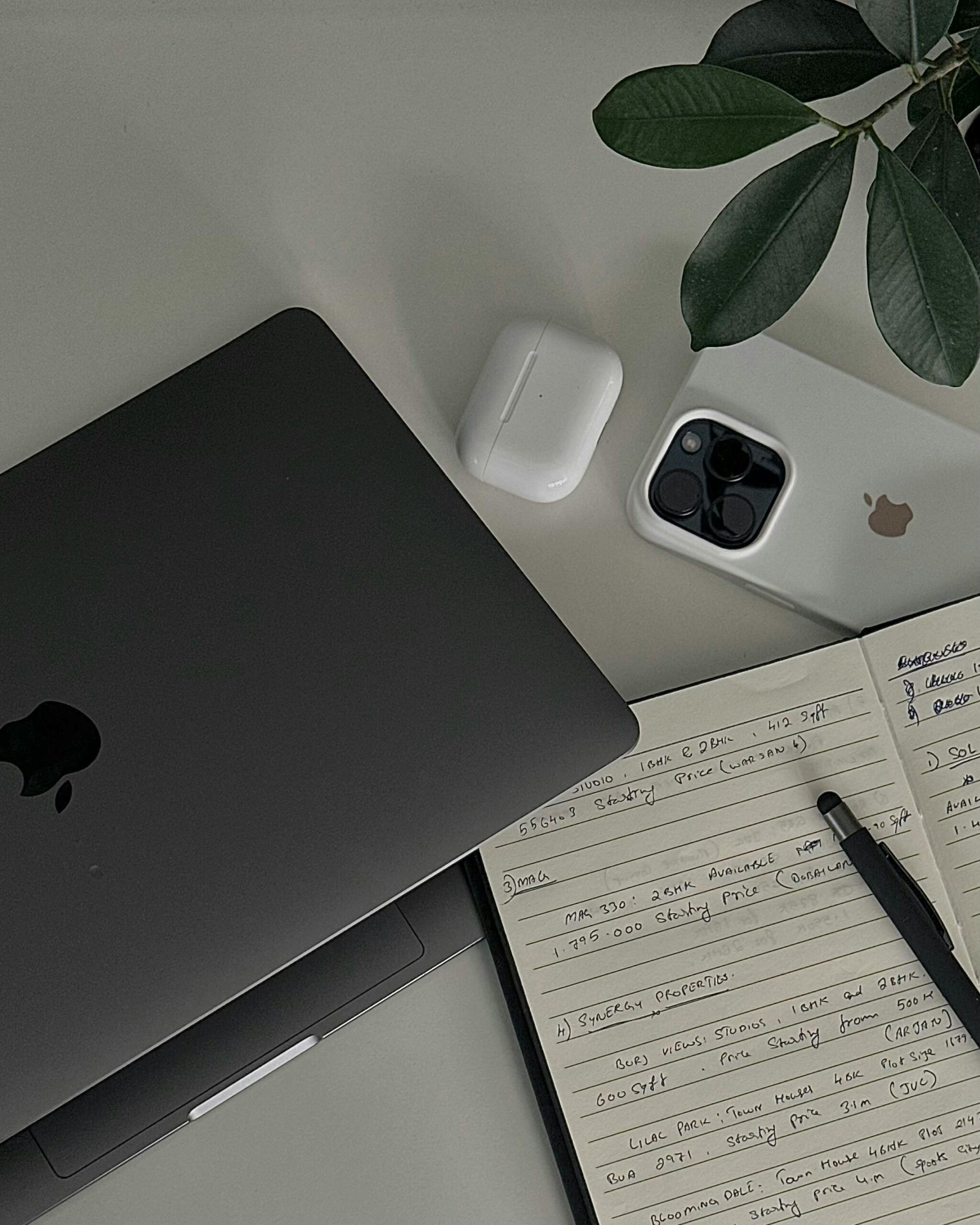 Flat lay of a modern workspace with Apple devices, notebook, and pen highlighting productivity.